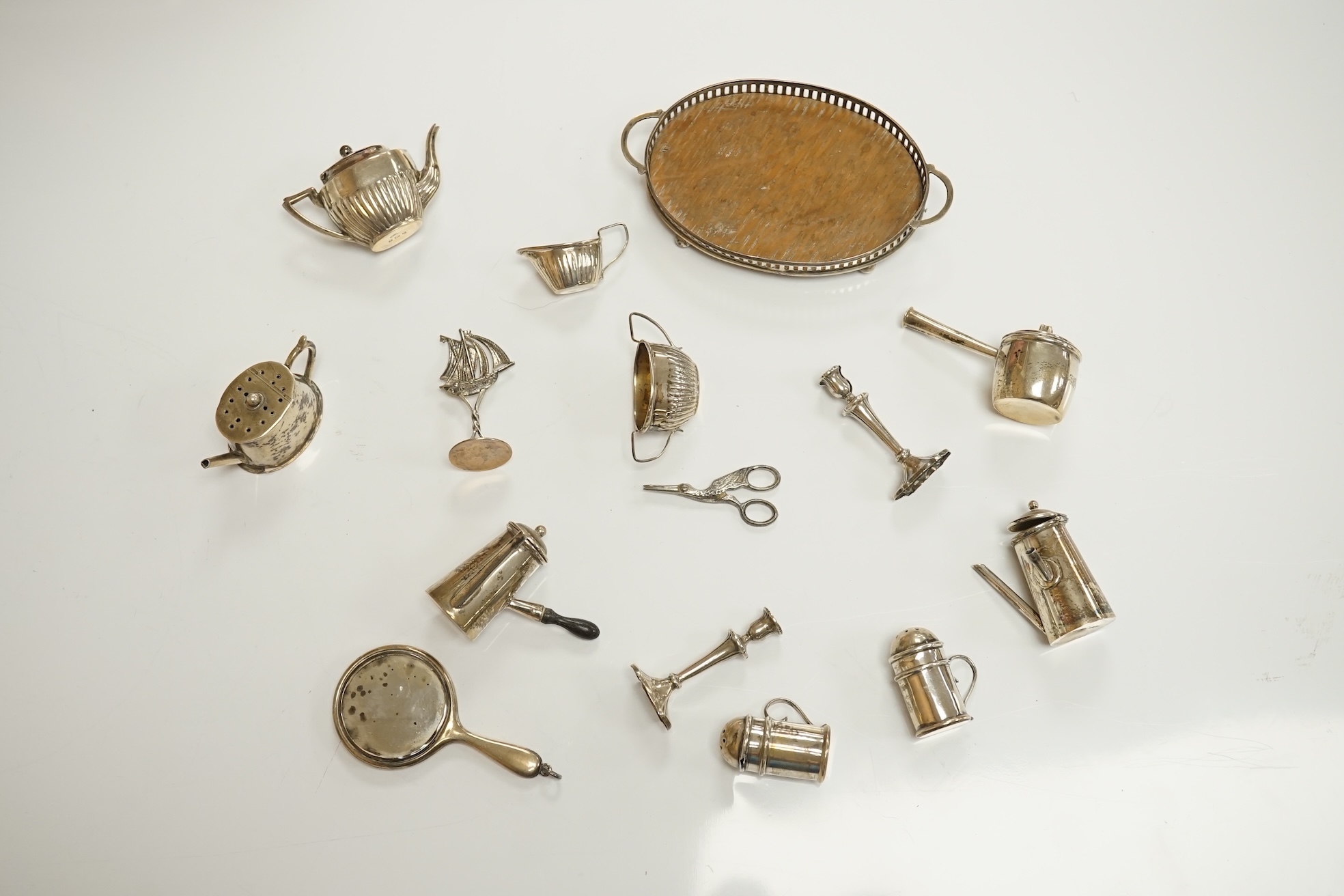 A collection of miniature silver including a three piece tea set and two handled tray by Saunders & Shepherd, Birmingham, 1904, tray 9.8cm, together with pepperettes including saucepan, candlesticks, hand mirror, etc. Co